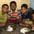 Four boys eat plates of rice and curry
