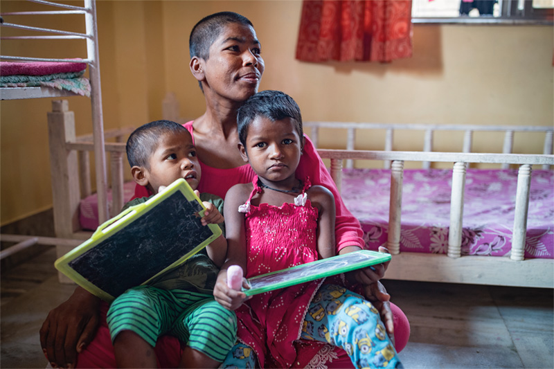 A mother sits with her two young children at a HOPE Mother and Childcare Unit in Kolkata