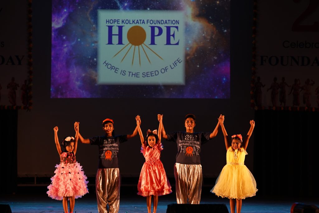 Children on stage at Foundation Day with a large HOPE banner in the background